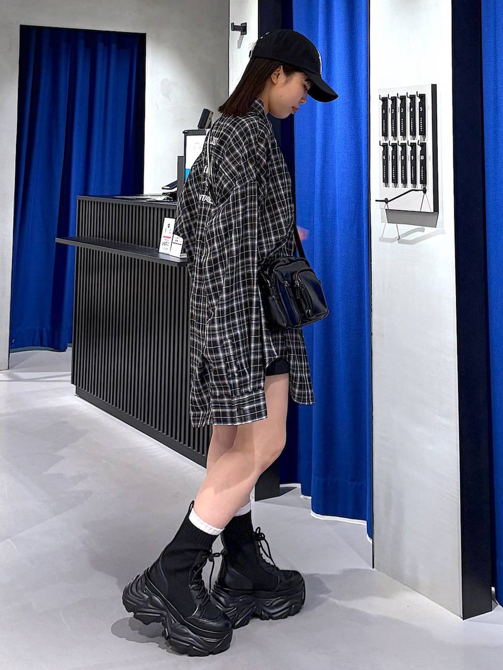 ブラック系のブーツ、ブラック系のスラックス、ブラック系のショルダーバッグを着用したレディースの春コーディネートの3枚目の写真