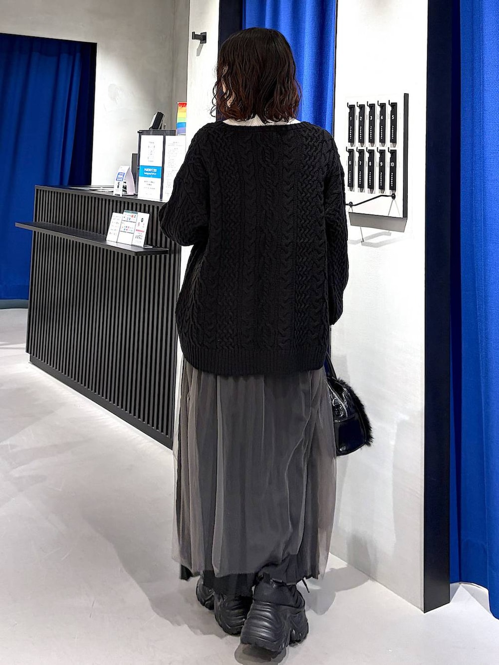 ブラック系のスニーカー、ブラック系のニット/セーター、ホワイト系のニット/セーターを着用したレディースの冬コーディネートの3枚目の写真