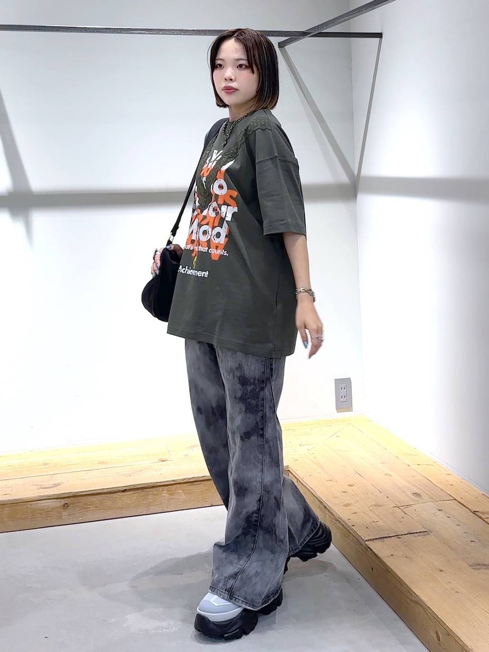 グレー系のスニーカー、ブラック系のデニムパンツ、ブラック系のショルダーバッグを着用したレディースの夏コーディネートの4枚目の写真