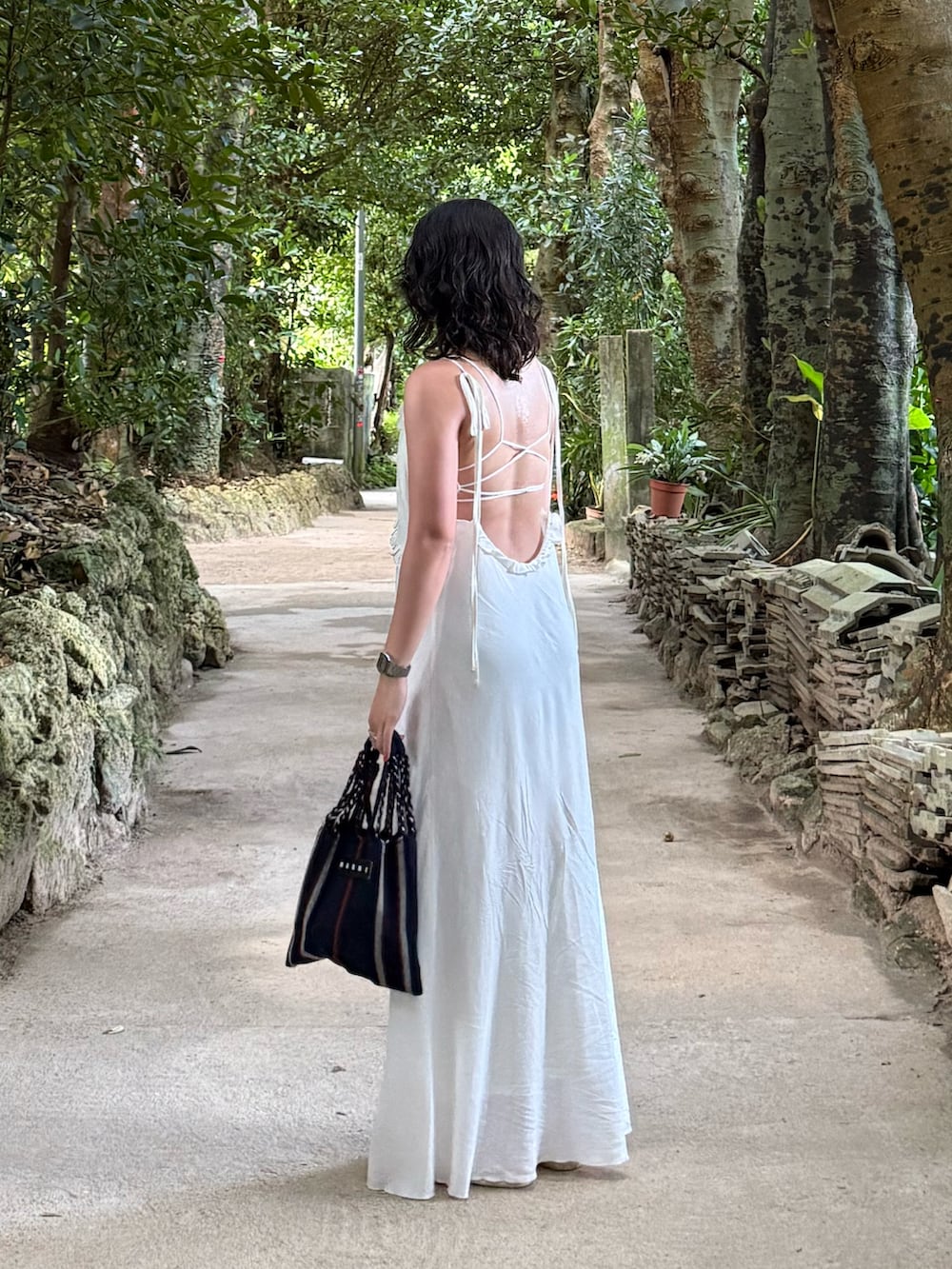 ホワイト系のワンピース、ホワイト系のサンダル、ブルー系のハンドバッグを着用したレディースの夏コーディネートの2枚目の写真