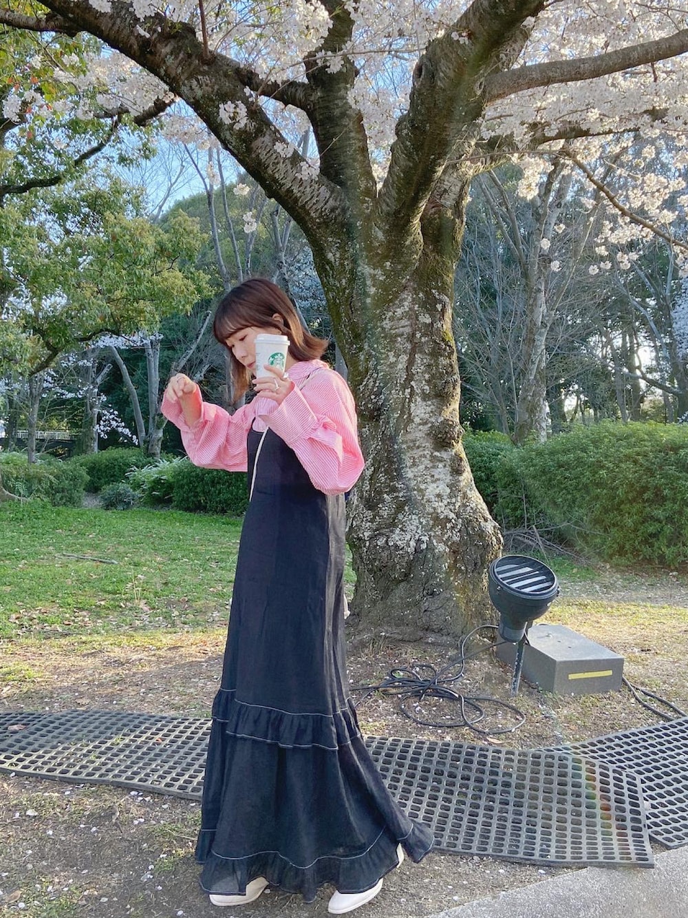 ブラック系のワンピース、ホワイト系のブーツ、ピンク系のトップスを着用したレディースの春コーディネートの2枚目の写真