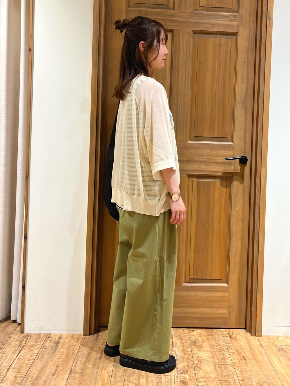 ブラック系のハンドバッグ、ベージュ系のニット/セーター、ホワイト系のTシャツ/カットソーを着用したレディースの夏コーディネートの4枚目の写真