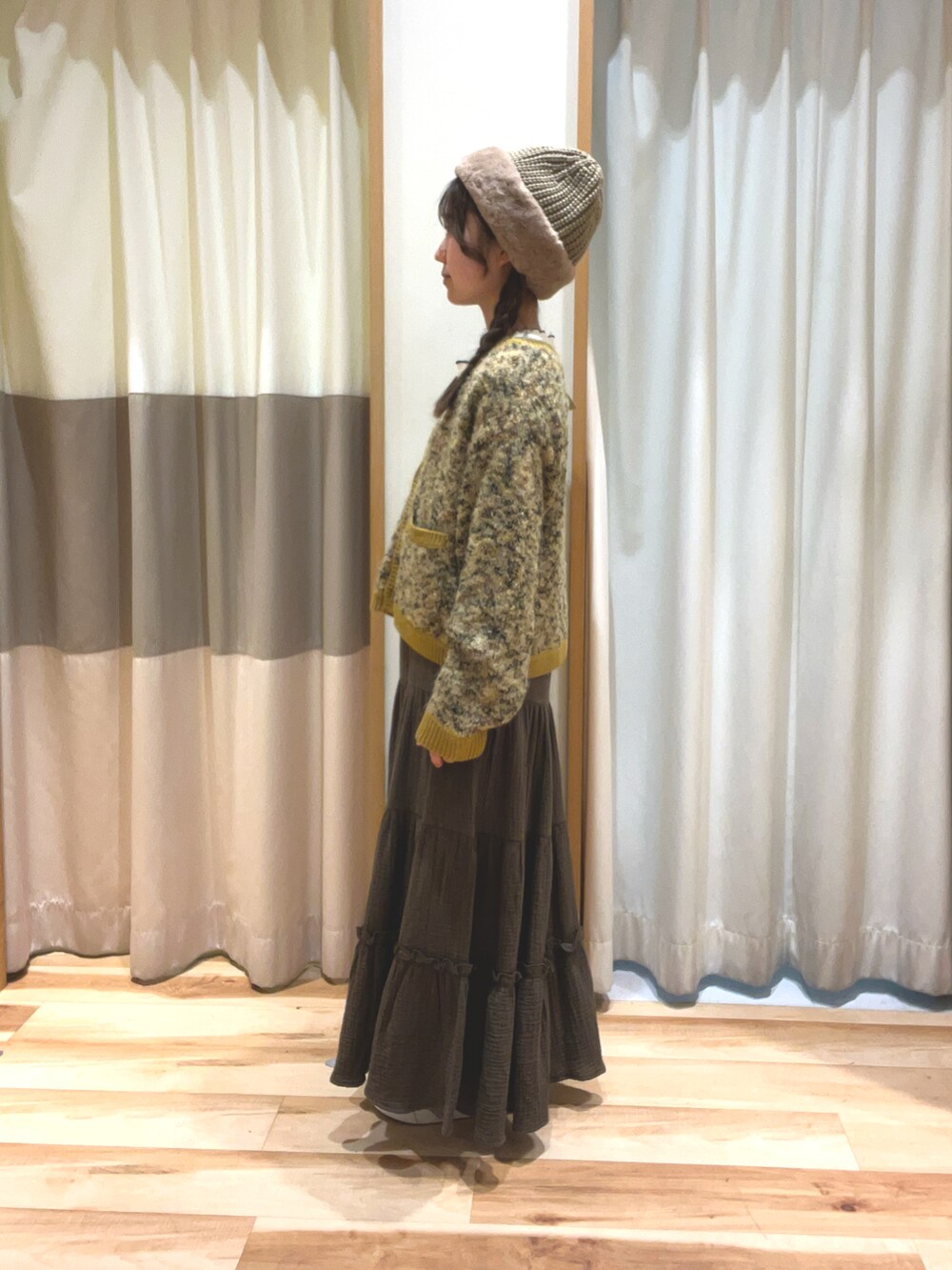 イエロー系のカーディガン/ボレロ、グリーン系のスカート、ホワイト系のTシャツ/カットソーを着用したレディースの冬コーディネートの3枚目の写真