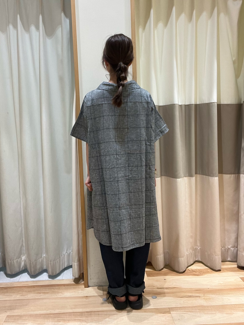 ブラック系のハンドバッグ、ブルー系のデニムパンツ、ブラック系のチュニックを着用したレディースの夏コーディネートの3枚目の写真