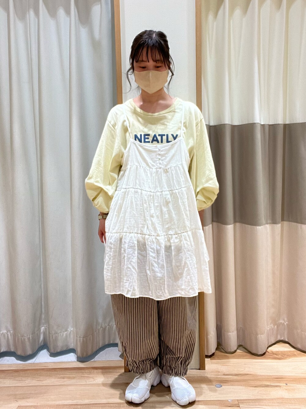 イエロー系のTシャツ/カットソー、ホワイト系のチュニック、グレー系のパンツを着用したレディースの春コーディネートの2枚目の写真