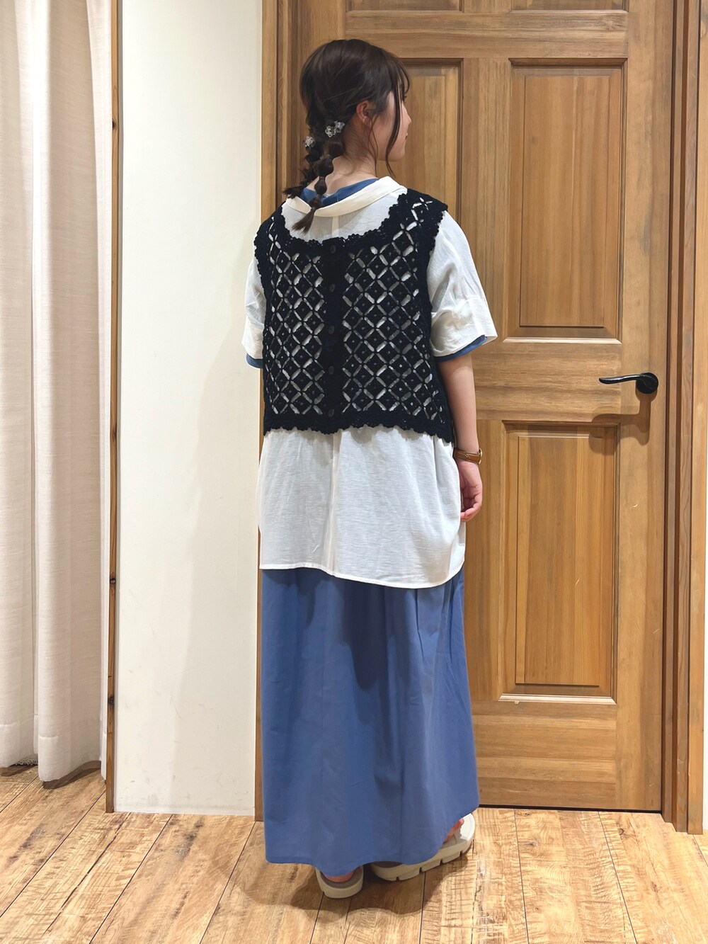 ホワイト系のサンダル、ブルー系のワンピース、ブラック系のベストを着用したレディースの夏コーディネートの4枚目の写真