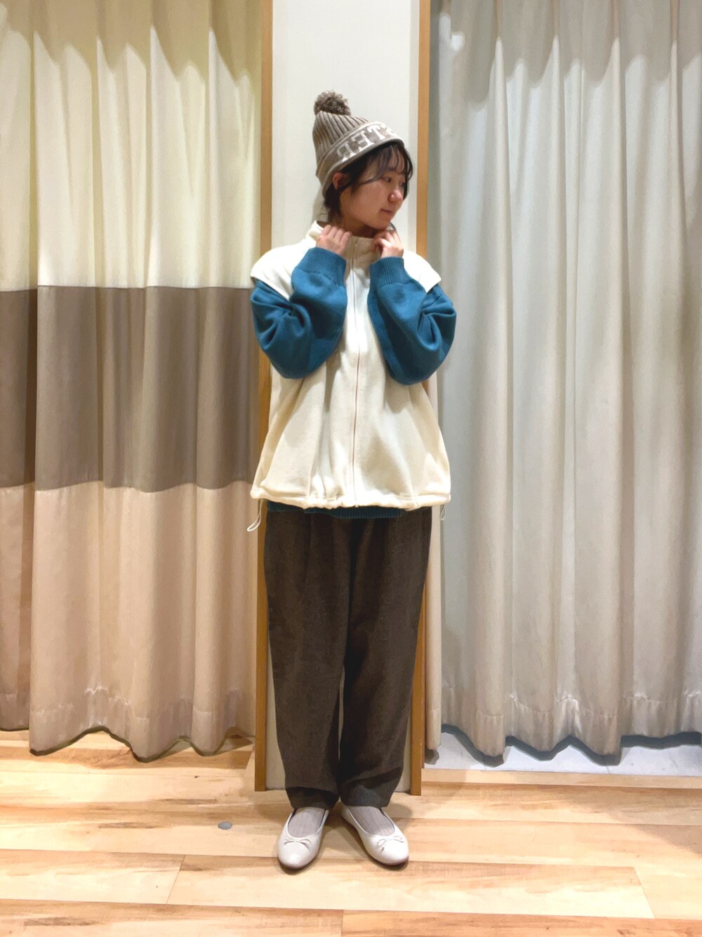 グレー系のその他パンツ、グリーン系のニット/セーター、ホワイト系のベストを着用したレディースの秋コーディネートの2枚目の写真