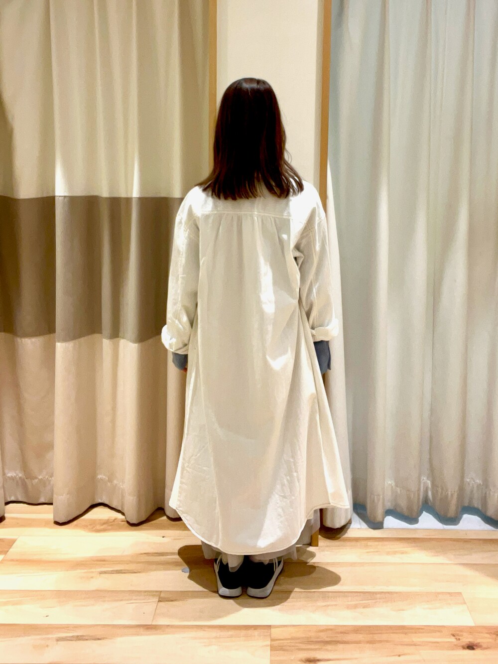 ブルー系のニット/セーター、グレー系のスカート、ホワイト系のワンピースを着用したレディースの春コーディネートの4枚目の写真