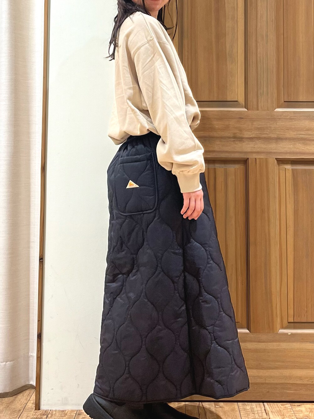 ブラック系のブーツ、ベージュ系のTシャツ/カットソー、ブラック系のスカートを着用したレディースの秋コーディネートの5枚目の写真