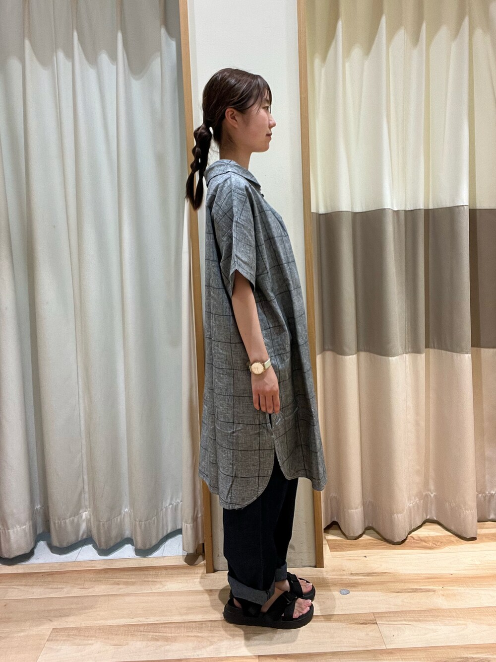 ブラック系のハンドバッグ、ブルー系のデニムパンツ、ブラック系のチュニックを着用したレディースの夏コーディネートの2枚目の写真