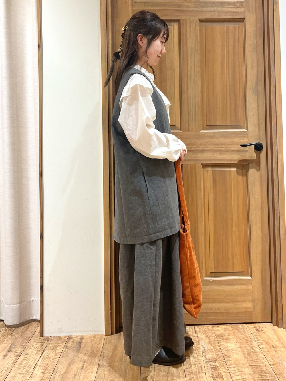 ブラック系のブーツ、ホワイト系のシャツ/ブラウス、ブラック系のベストを着用したレディースの秋コーディネートの5枚目の写真