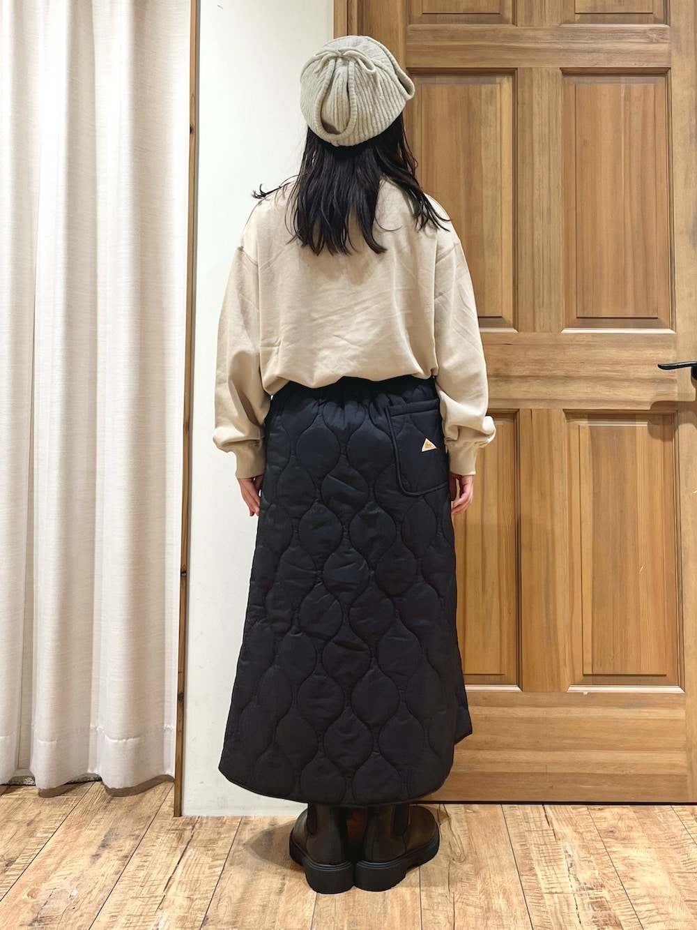 ブラック系のブーツ、ベージュ系のTシャツ/カットソー、ブラック系のスカートを着用したレディースの秋コーディネートの3枚目の写真