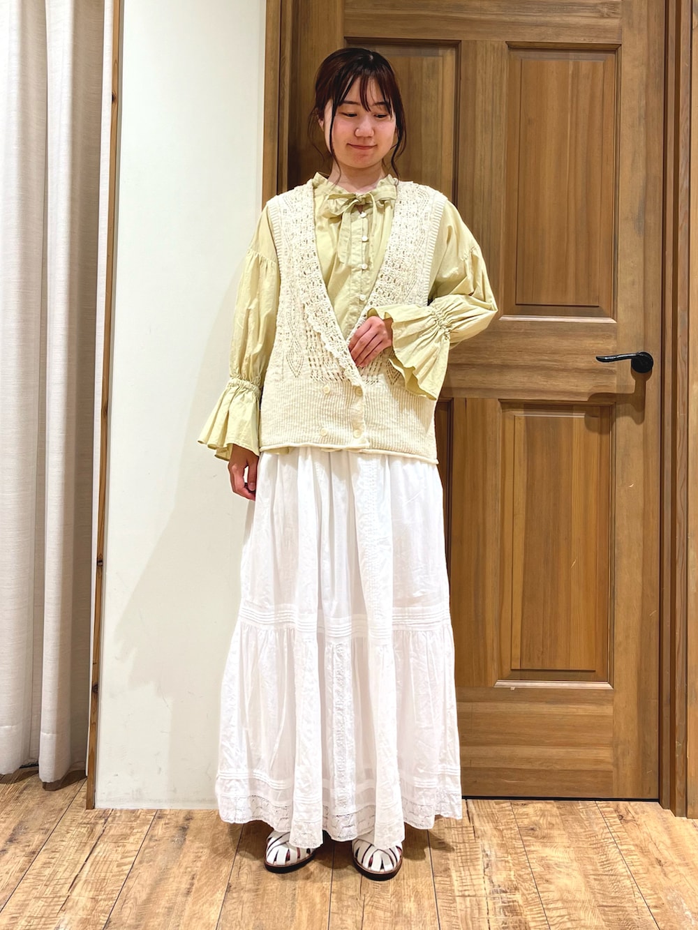 イエロー系のシャツ/ブラウス、ホワイト系のニット/セーター、ホワイト系のスカートを着用したレディースの夏コーディネートの2枚目の写真