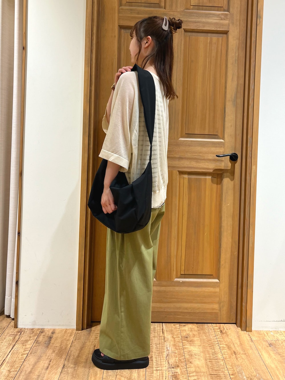 ブラック系のハンドバッグ、ベージュ系のニット/セーター、ホワイト系のTシャツ/カットソーを着用したレディースの夏コーディネートの5枚目の写真