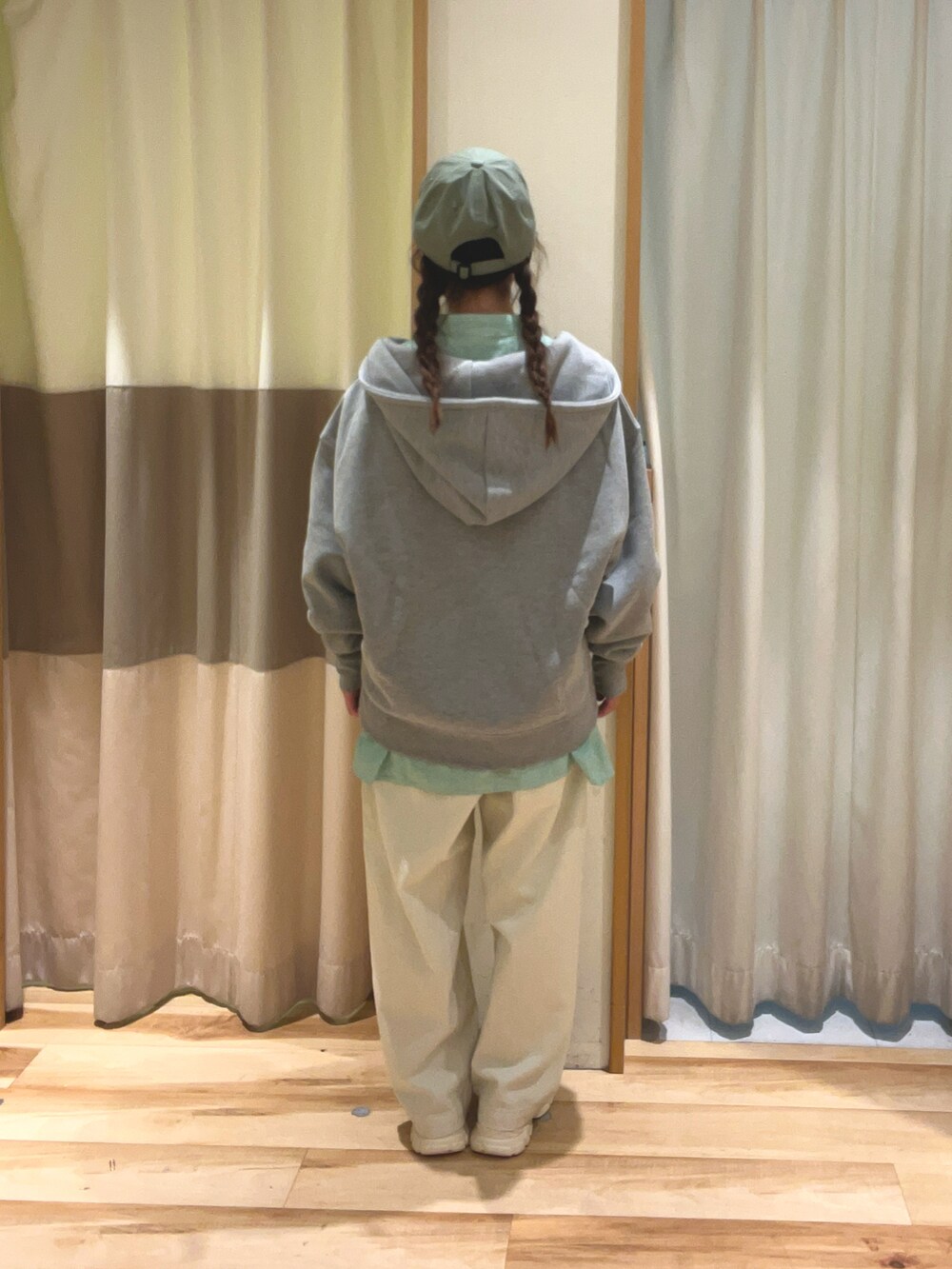 グリーン系のチュニック、グレー系のTシャツ/カットソー、ホワイト系のデニムパンツを着用したレディースの冬コーディネートの4枚目の写真