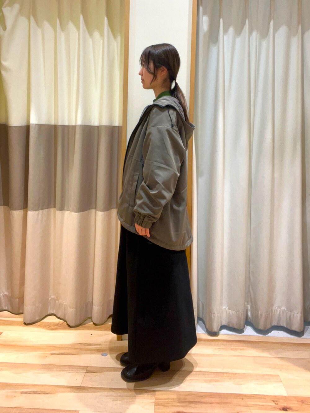 グリーン系のニット/セーター、ブラック系のスカート、ブラック系のドレスシューズを着用したレディースの秋コーディネートの2枚目の写真