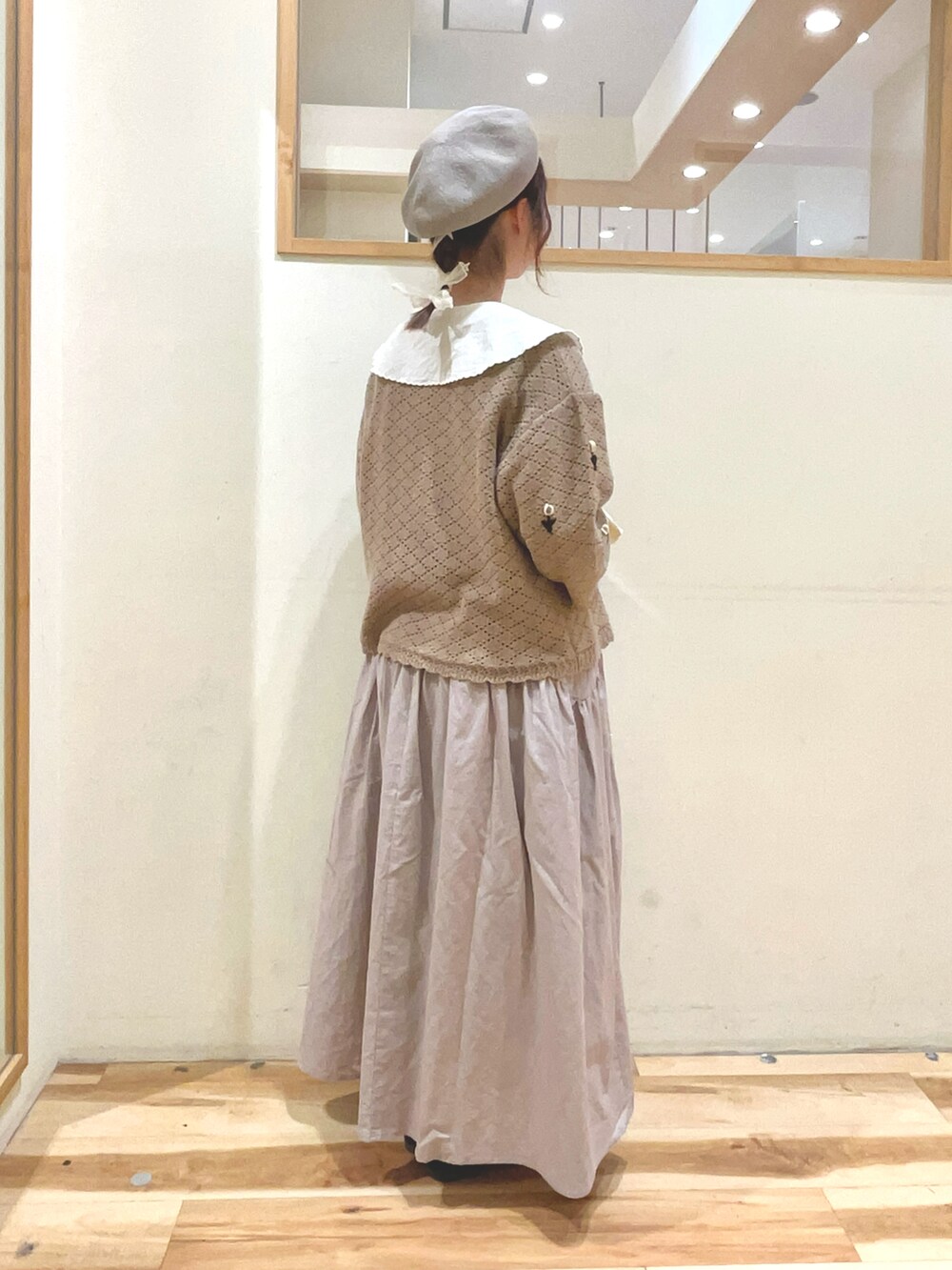 シルバー系のハンドバッグ、ベージュ系のスカート、ブラック系のサンダルを着用したレディースの春コーディネートの4枚目の写真