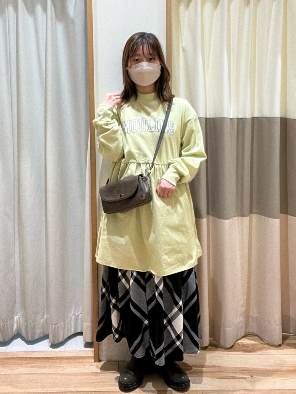 ブラウン系のショルダーバッグ、ブラック系のスカート、グリーン系のTシャツ/カットソーを着用したレディースの冬コーディネートの2枚目の写真