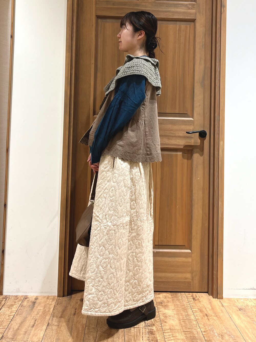 ブラウン系のハンドバッグ、ブラウン系のベスト、ブルー系のシャツ/ブラウスを着用したレディースの秋コーディネートの2枚目の写真