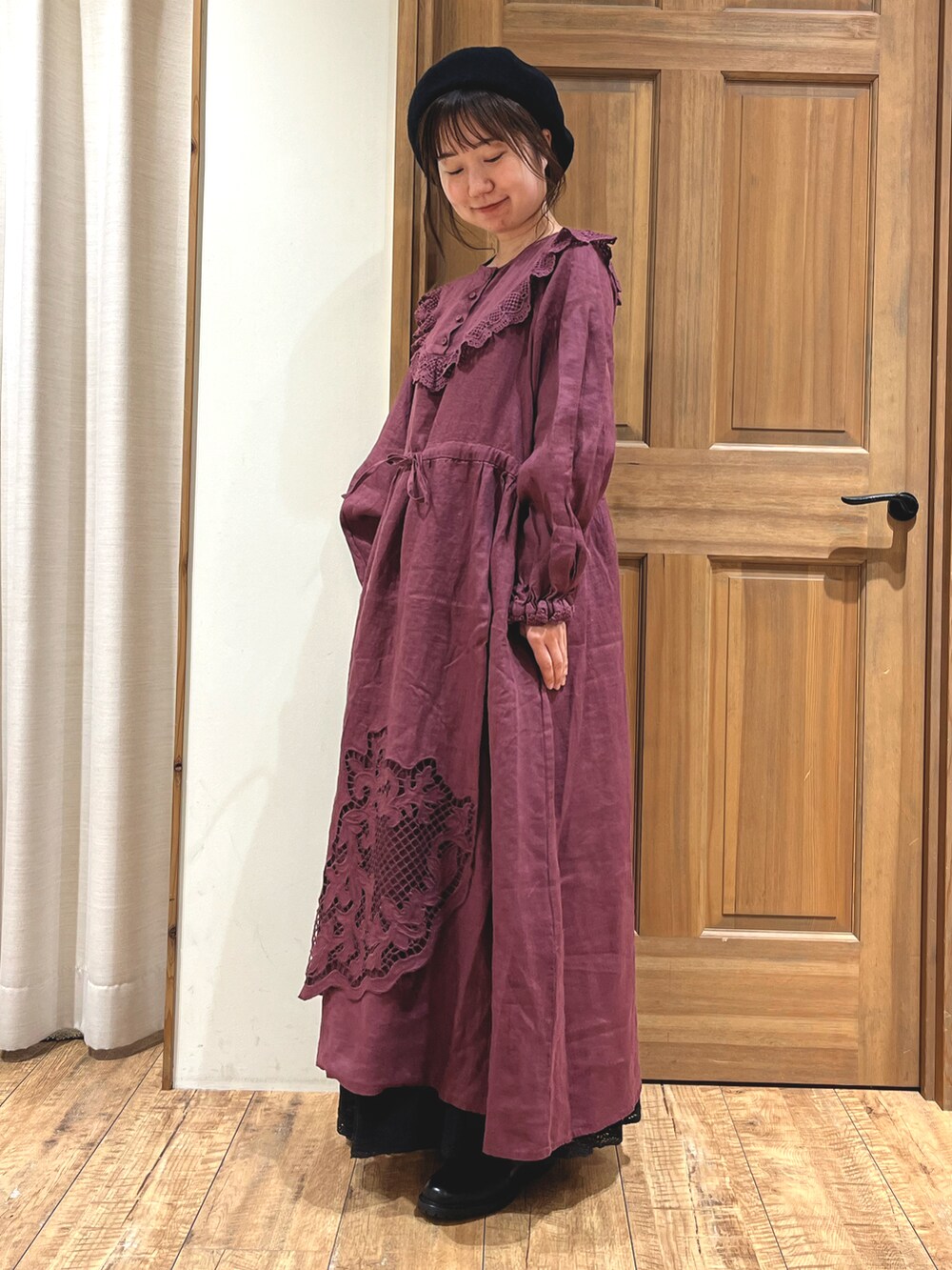 レッド系のワンピース、ブラック系のスカート、ブラック系のブーツを着用したレディースの秋コーディネートの2枚目の写真