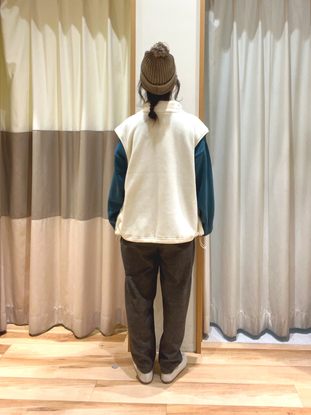 グレー系のその他パンツ、グリーン系のニット/セーター、ホワイト系のベストを着用したレディースの秋コーディネートの4枚目の写真