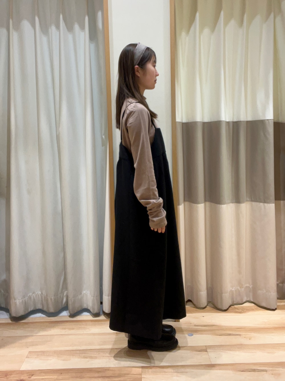 ブラック系のワンピース、ブラック系のブーツ、ブラウン系のネックレスを着用したレディースの秋コーディネートの2枚目の写真