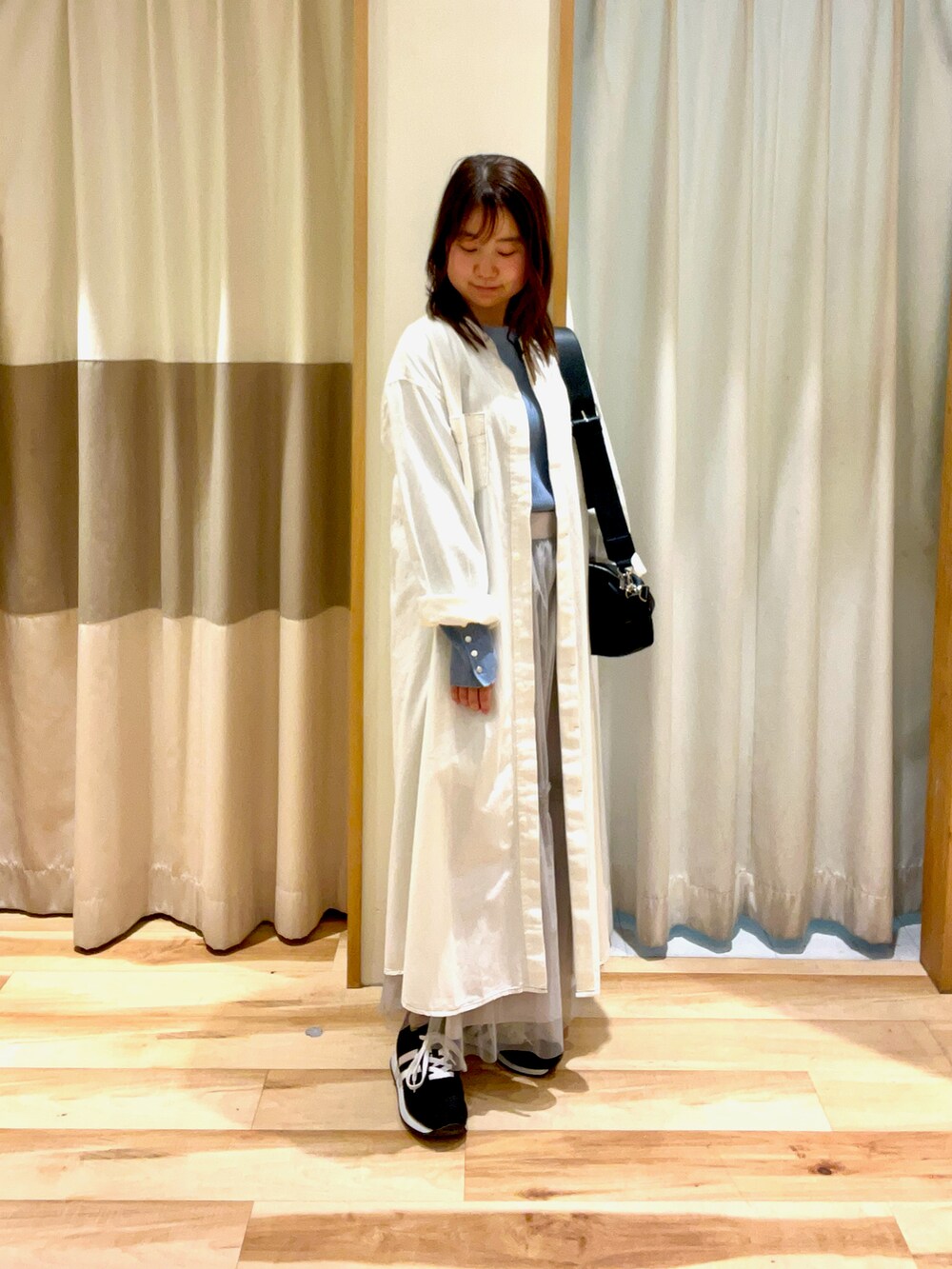 ブルー系のニット/セーター、グレー系のスカート、ホワイト系のワンピースを着用したレディースの春コーディネートの2枚目の写真