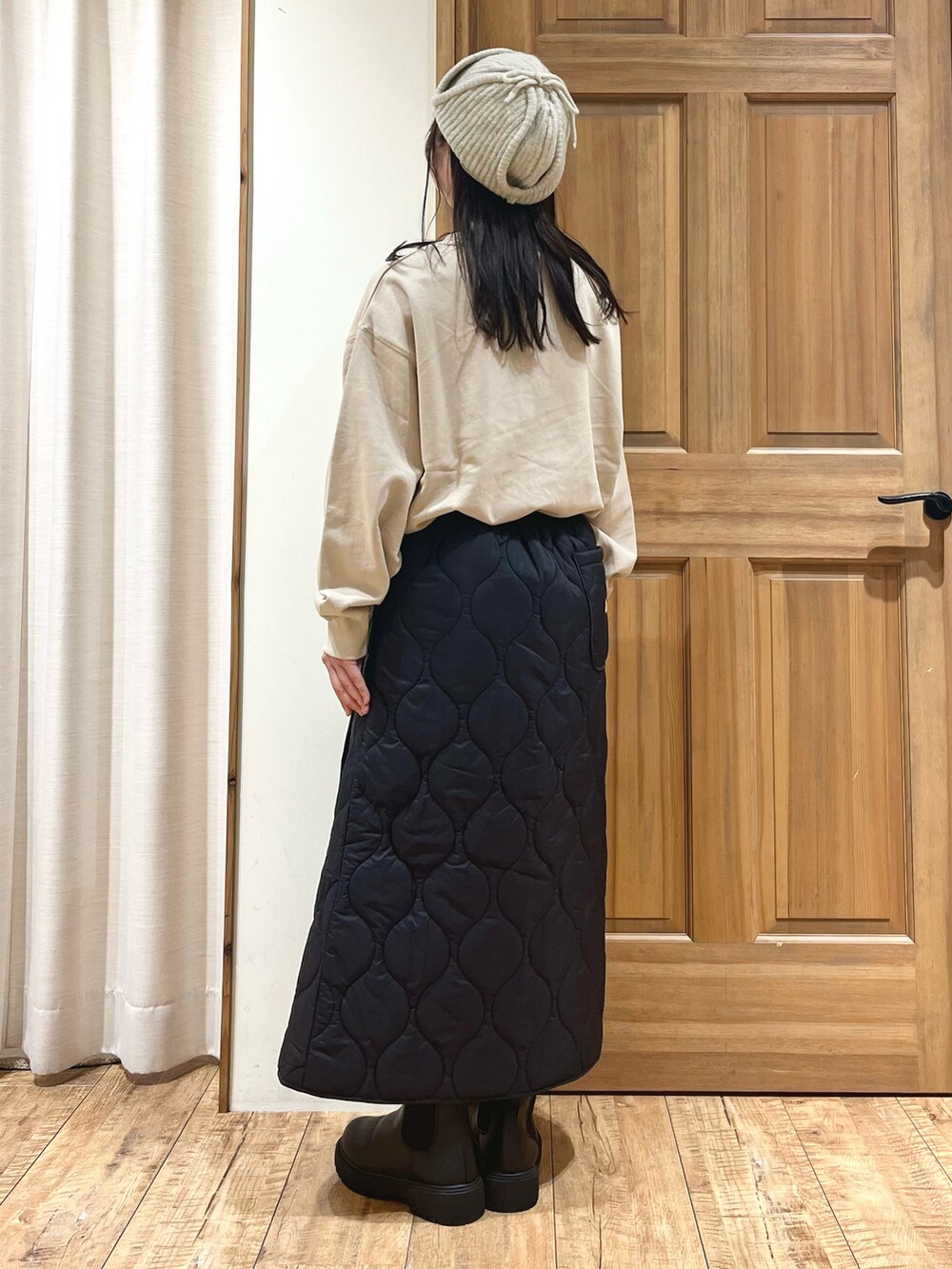 ブラック系のブーツ、ベージュ系のTシャツ/カットソー、ブラック系のスカートを着用したレディースの秋コーディネートの2枚目の写真