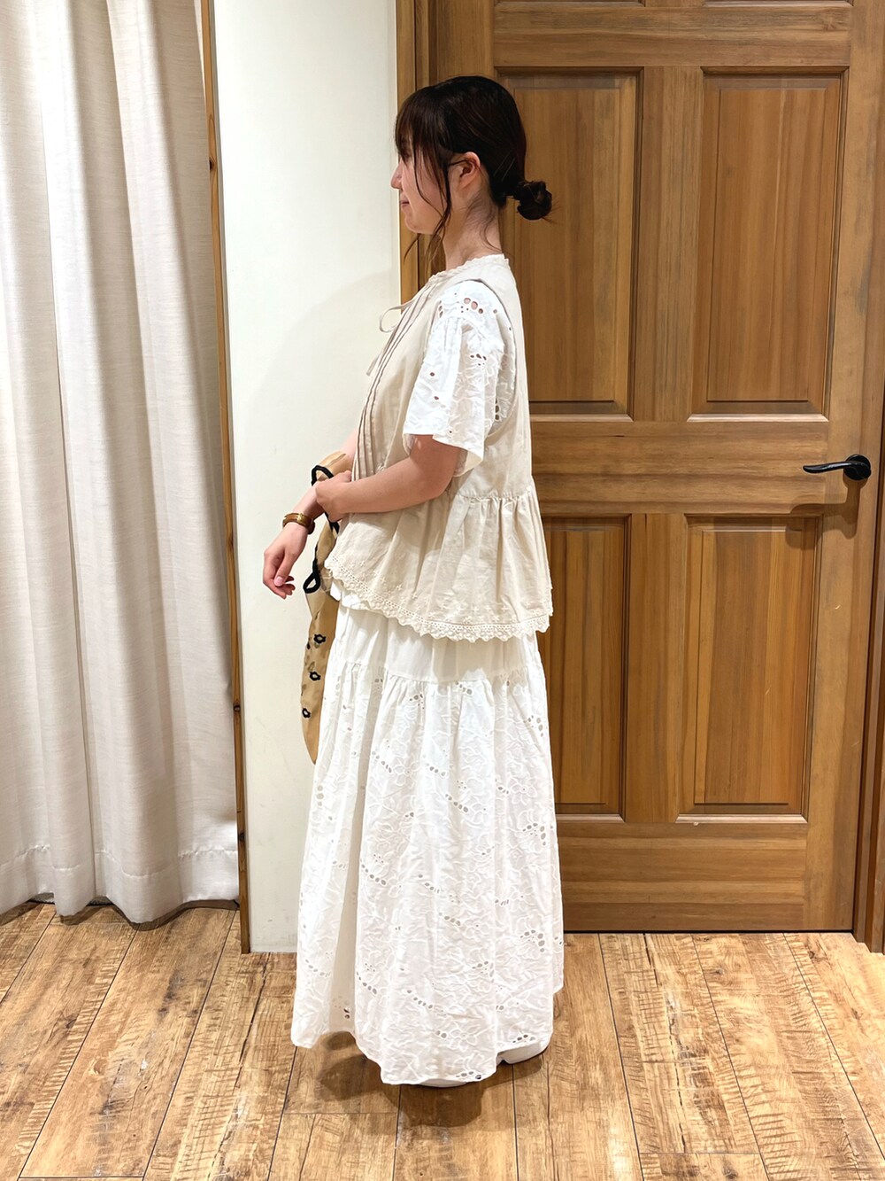 ベージュ系のサンダル、ベージュ系のハンドバッグ、ホワイト系のスカートを着用したレディースの夏コーディネートの2枚目の写真