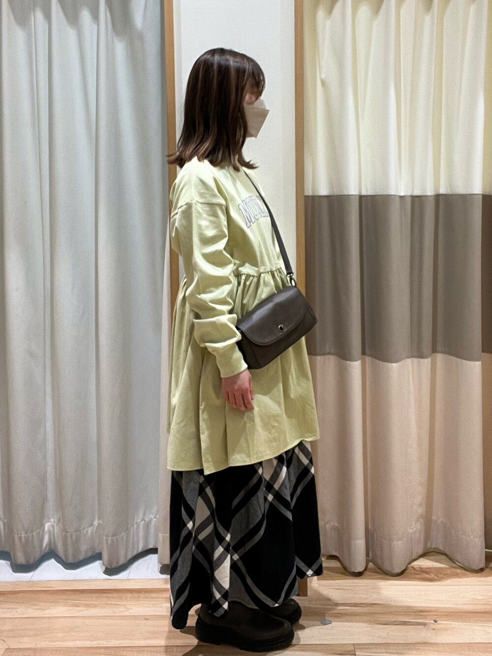 ブラウン系のショルダーバッグ、ブラック系のスカート、グリーン系のTシャツ/カットソーを着用したレディースの冬コーディネートの3枚目の写真
