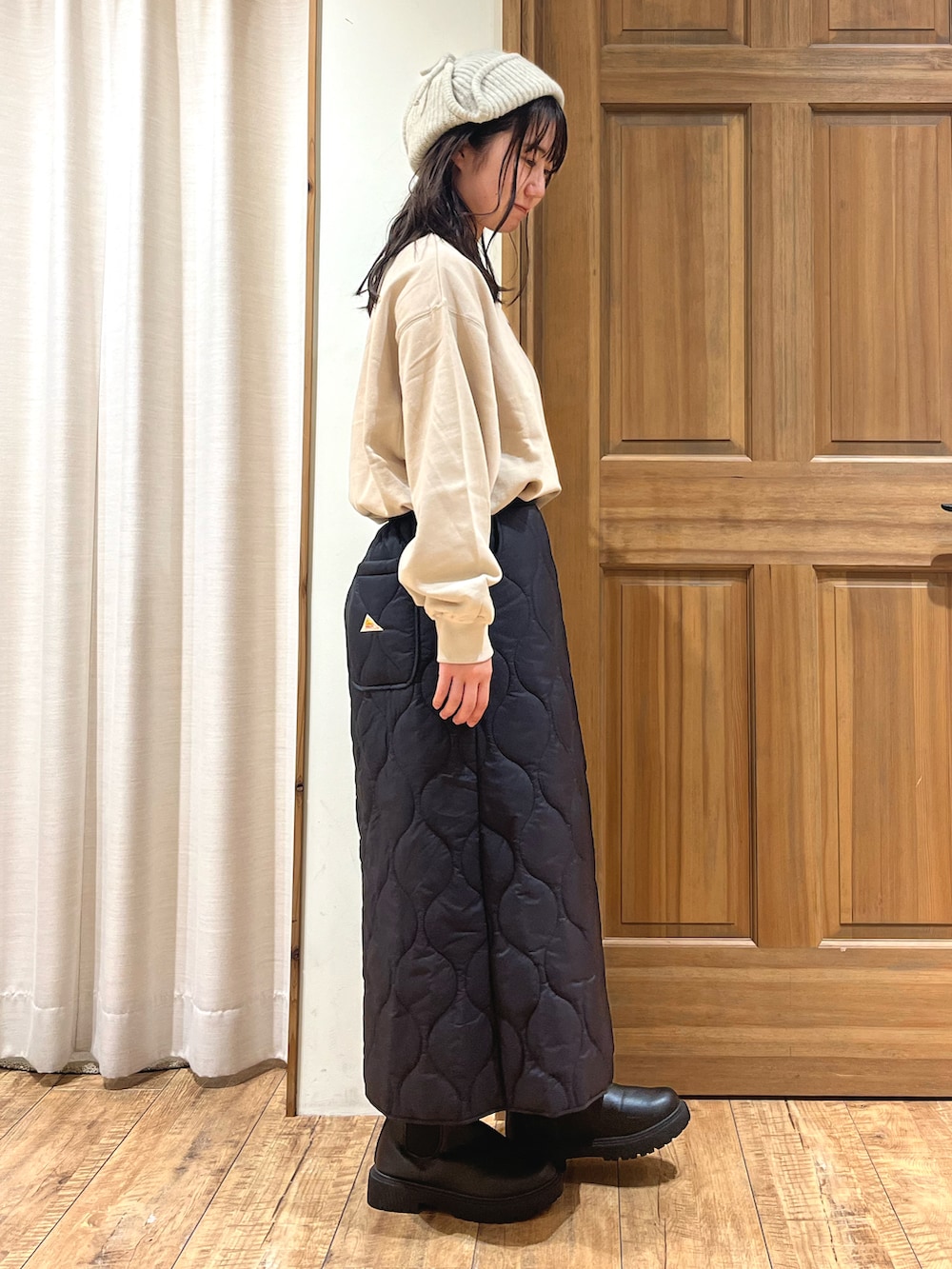 ブラック系のブーツ、ベージュ系のTシャツ/カットソー、ブラック系のスカートを着用したレディースの秋コーディネートの4枚目の写真