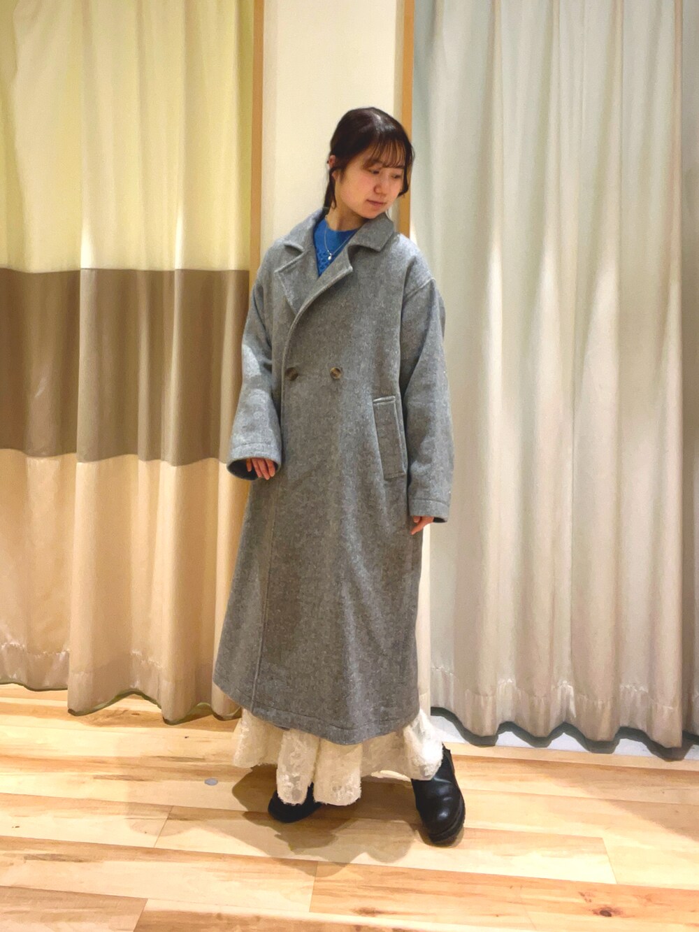 ブルー系のニット/セーター、ホワイト系のスカート、グレー系のその他アウターを着用したレディースの冬コーディネートの2枚目の写真