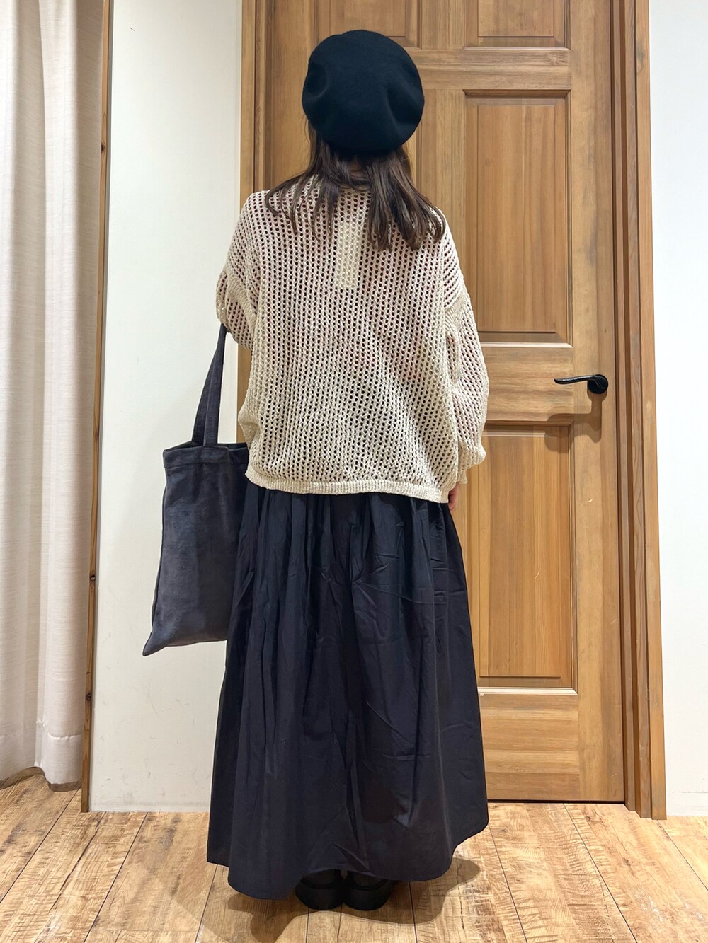 グレー系のハンドバッグ、グレー系のスカート、レッド系のニット/セーターを着用したレディースの秋コーディネートの5枚目の写真