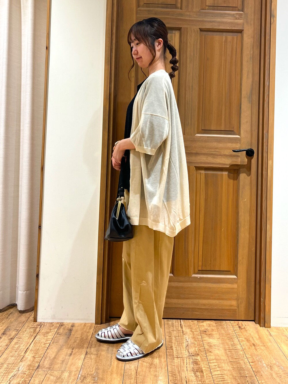 シルバー系のサンダル、ブラック系のハンドバッグ、ブラック系のTシャツ/カットソーを着用したレディースの夏コーディネートの3枚目の写真