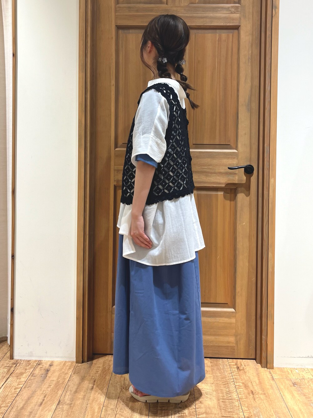 ホワイト系のサンダル、ブルー系のワンピース、ブラック系のベストを着用したレディースの夏コーディネートの3枚目の写真