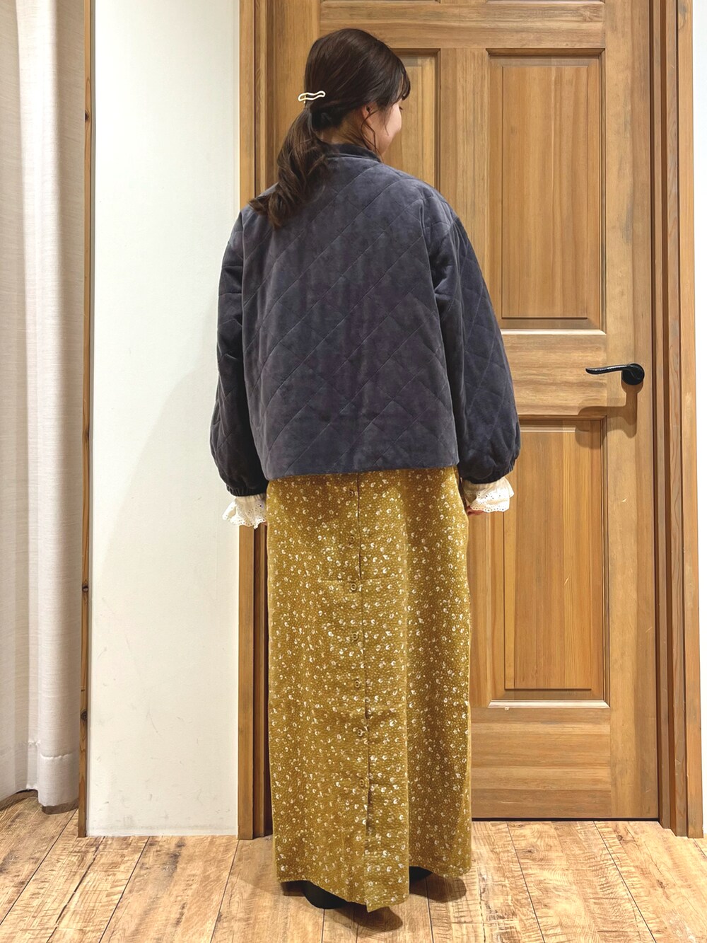 イエロー系のワンピース、ブラック系のドレスシューズ、グレー系のノーカラージャケットを着用したレディースの秋コーディネートの5枚目の写真