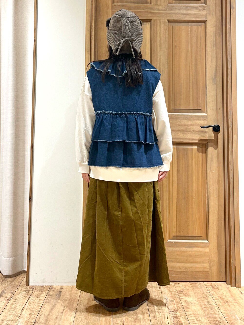 ホワイト系のTシャツ/カットソー、ブルー系のベスト、グリーン系のスカートを着用したレディースの秋コーディネートの4枚目の写真