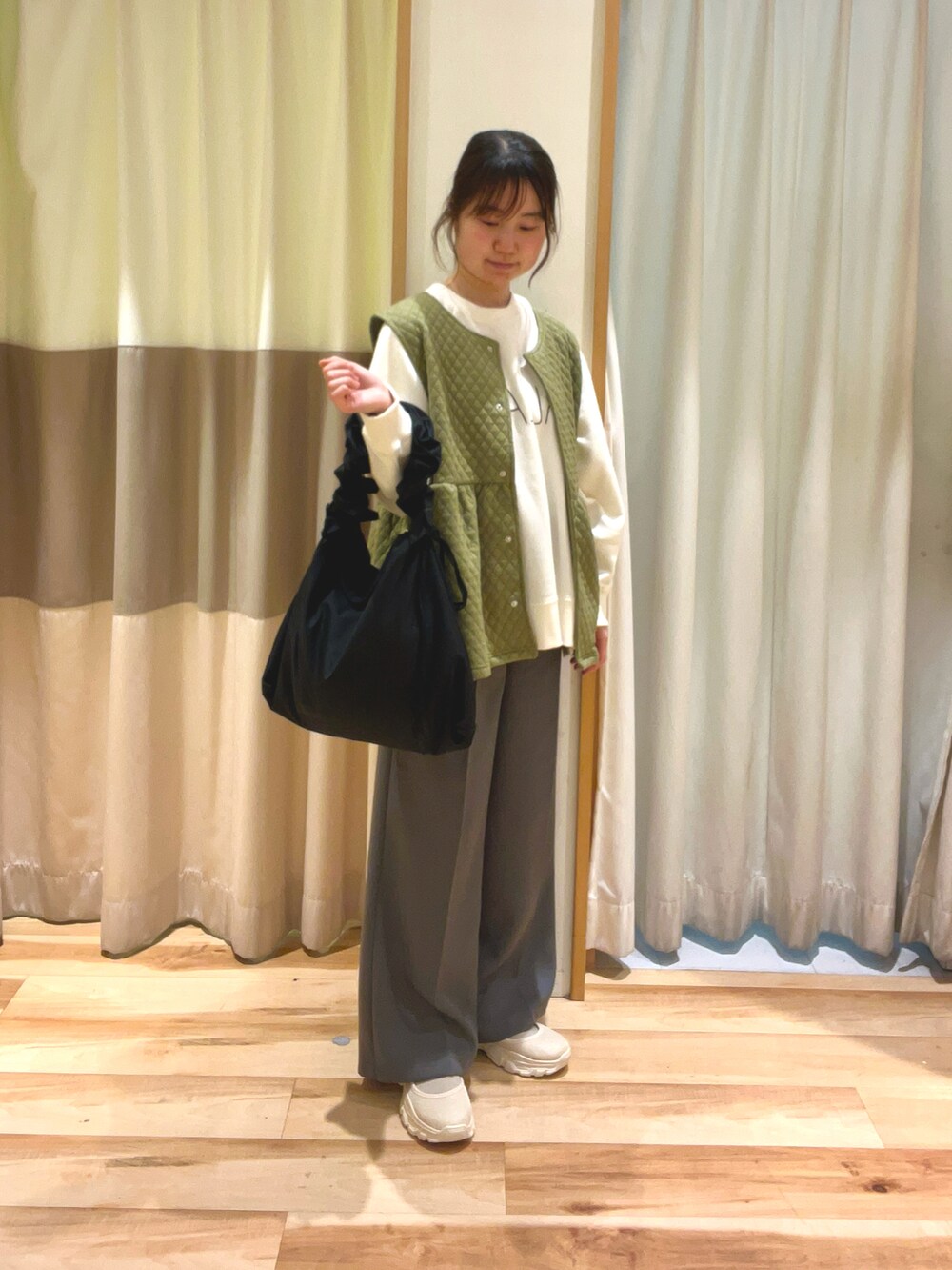 ホワイト系のTシャツ/カットソー、グリーン系のベスト、ブラック系のハンドバッグを着用したレディースの冬コーディネートの2枚目の写真