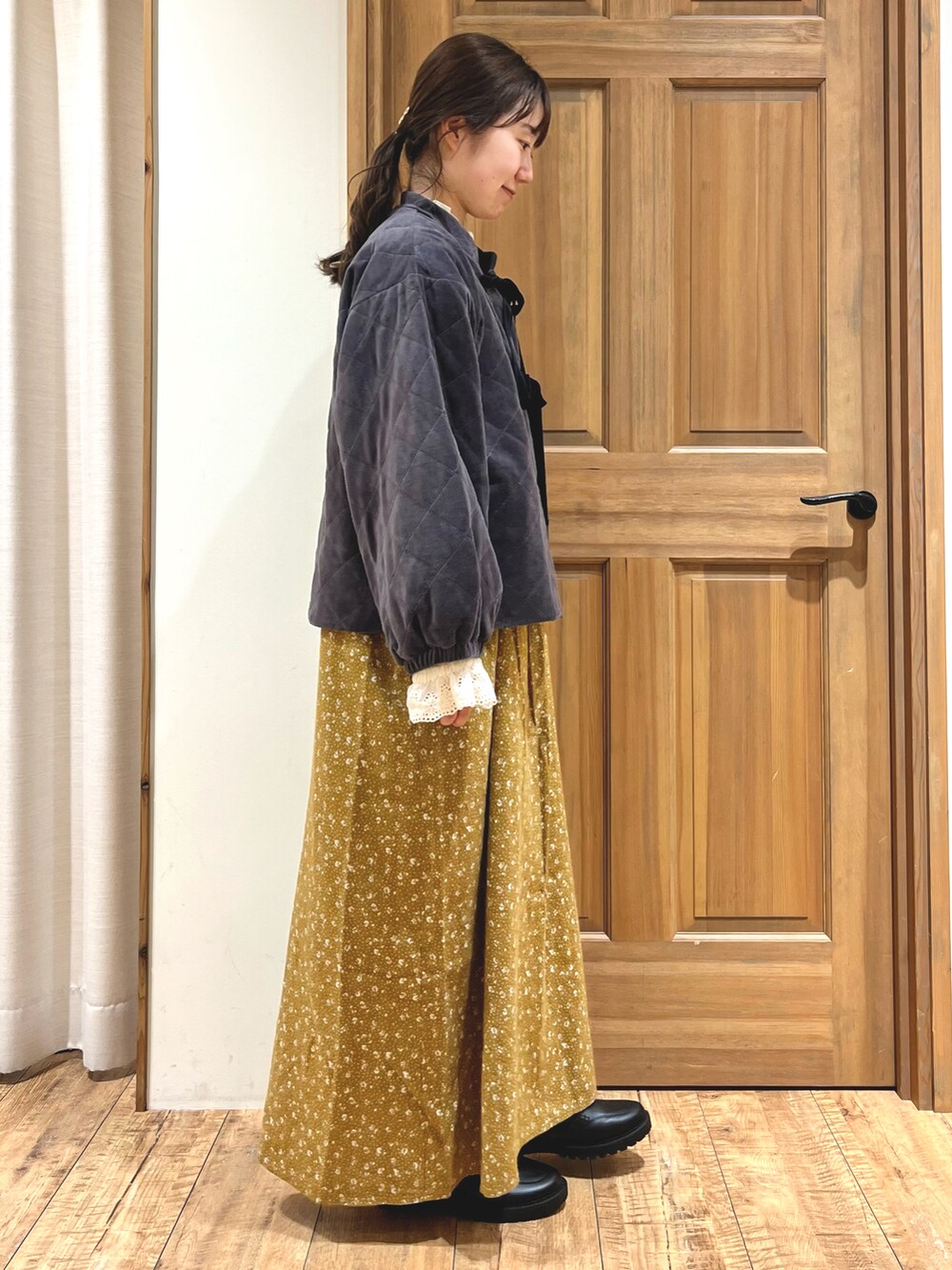イエロー系のワンピース、ブラック系のドレスシューズ、グレー系のノーカラージャケットを着用したレディースの秋コーディネートの4枚目の写真