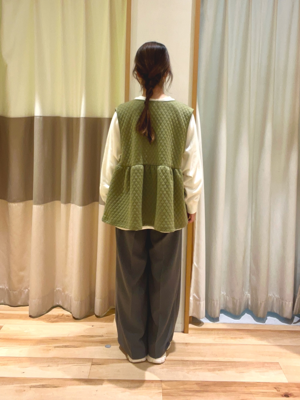 ホワイト系のTシャツ/カットソー、グリーン系のベスト、ブラック系のハンドバッグを着用したレディースの冬コーディネートの5枚目の写真