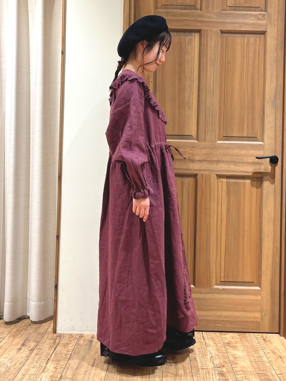 レッド系のワンピース、ブラック系のスカート、ブラック系のブーツを着用したレディースの秋コーディネートの5枚目の写真