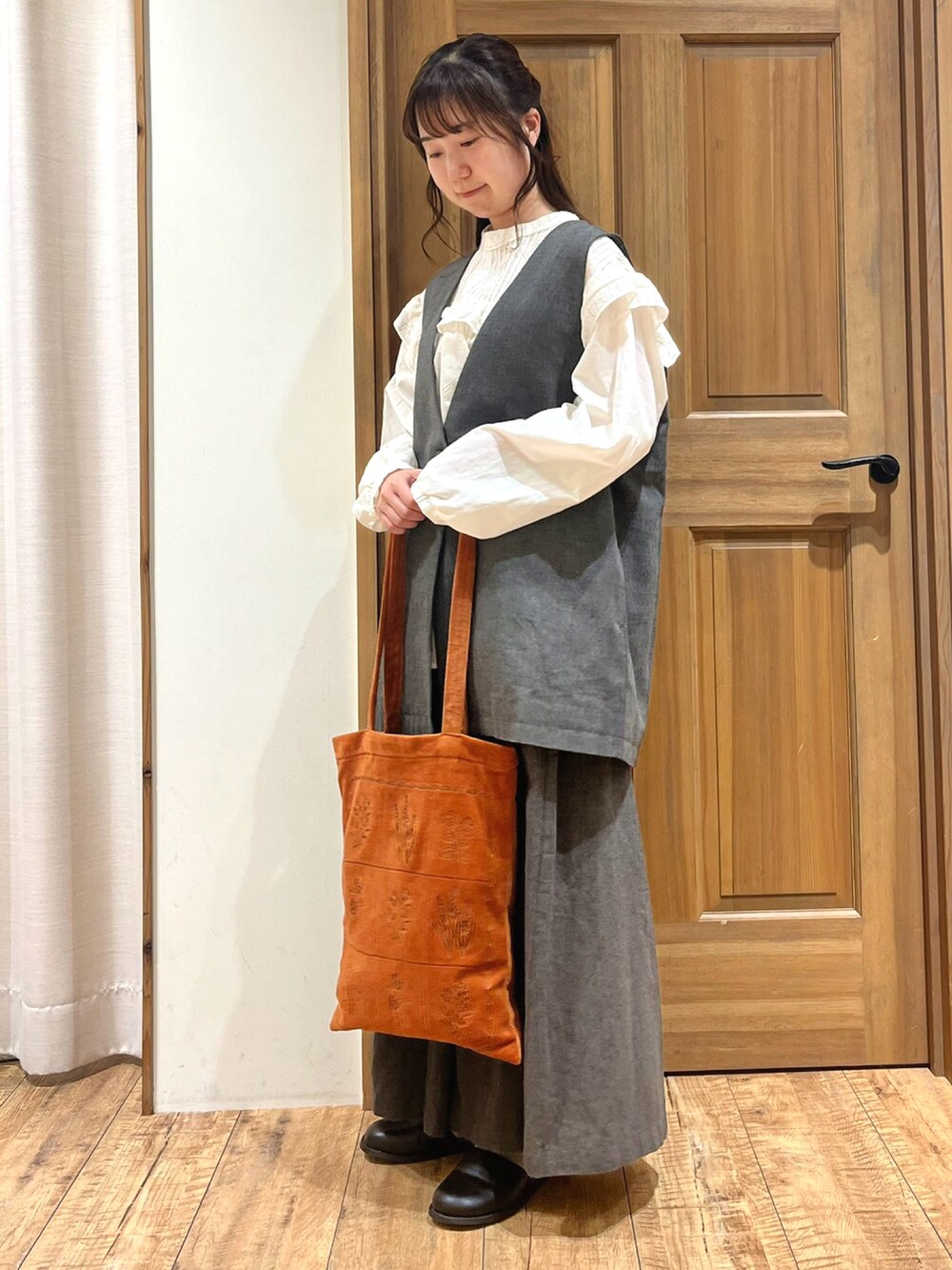 ブラック系のブーツ、ホワイト系のシャツ/ブラウス、ブラック系のベストを着用したレディースの秋コーディネートの2枚目の写真