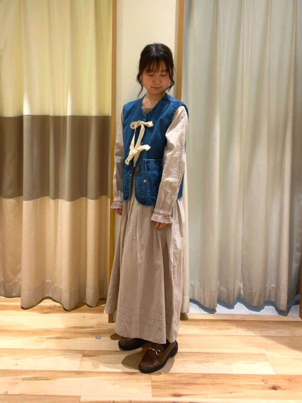 ベージュ系のワンピース、ブルー系のベストを着用したレディースの冬コーディネートの2枚目の写真