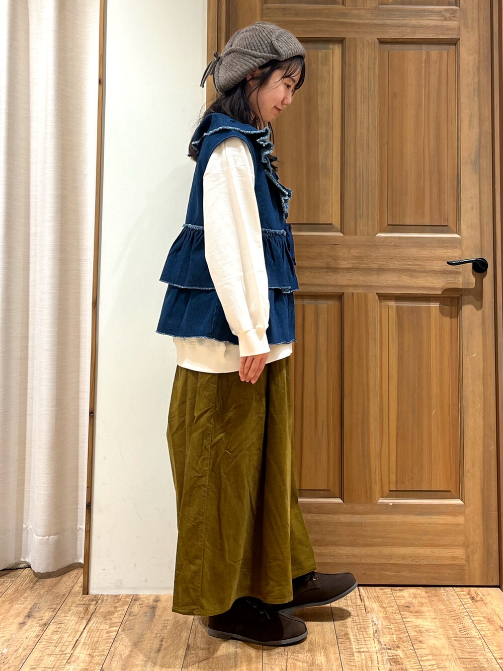 ホワイト系のTシャツ/カットソー、ブルー系のベスト、グリーン系のスカートを着用したレディースの秋コーディネートの5枚目の写真