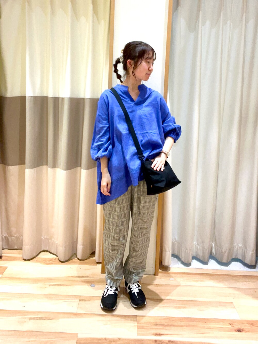 ブラック系のハンドバッグ、ブルー系のシャツ/ブラウス、グリーン系のスラックスを着用したレディースの春コーディネートの2枚目の写真