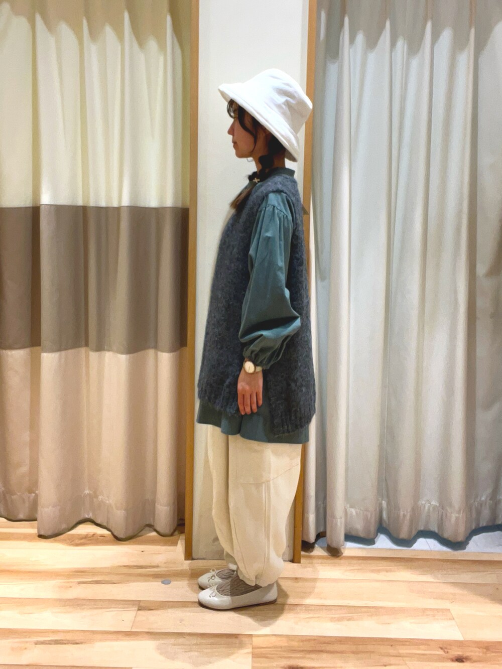 グレー系のベスト、グリーン系のチュニック、ホワイト系のカーゴパンツを着用したレディースの秋コーディネートの2枚目の写真