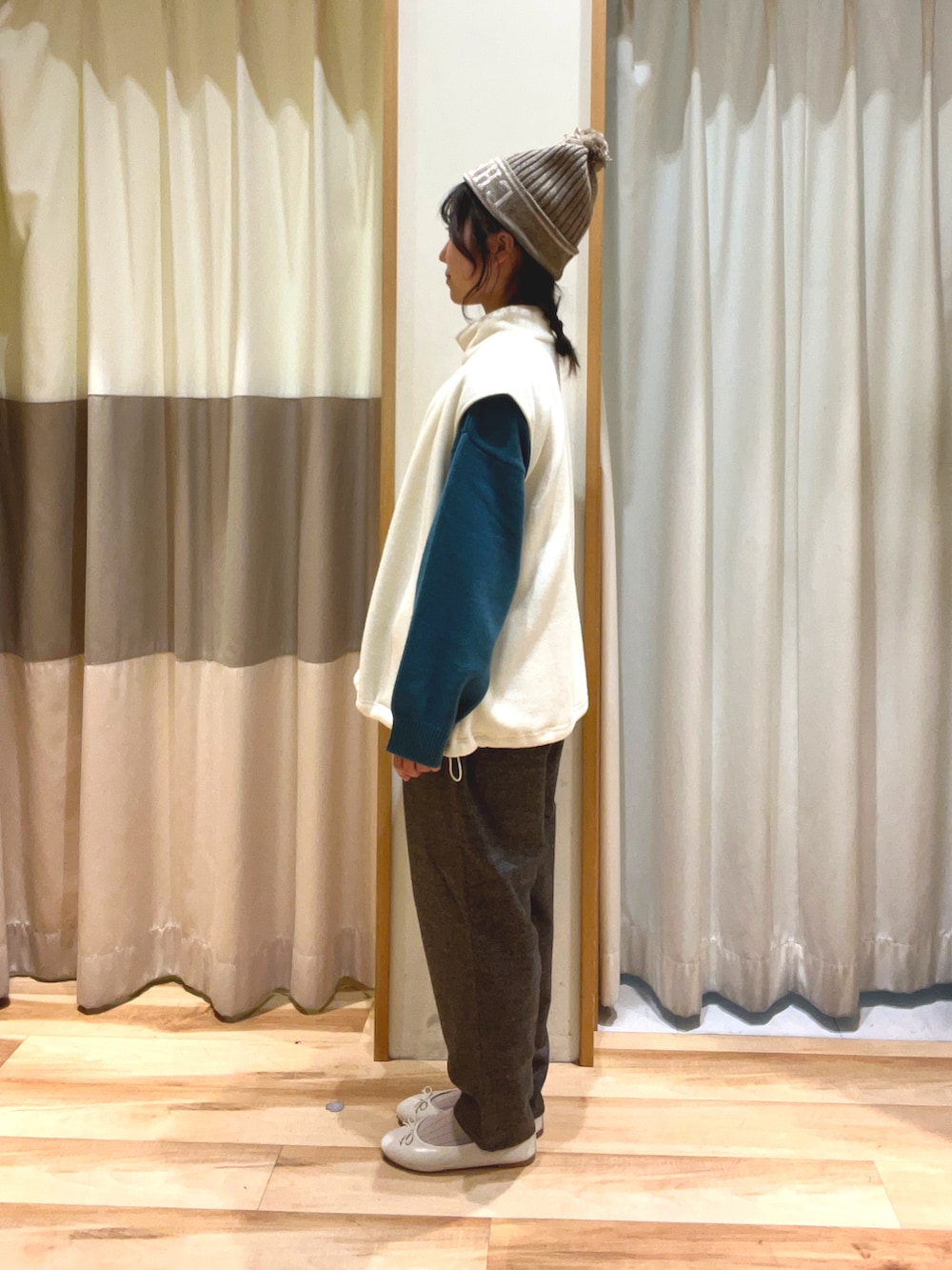 グレー系のその他パンツ、グリーン系のニット/セーター、ホワイト系のベストを着用したレディースの秋コーディネートの3枚目の写真