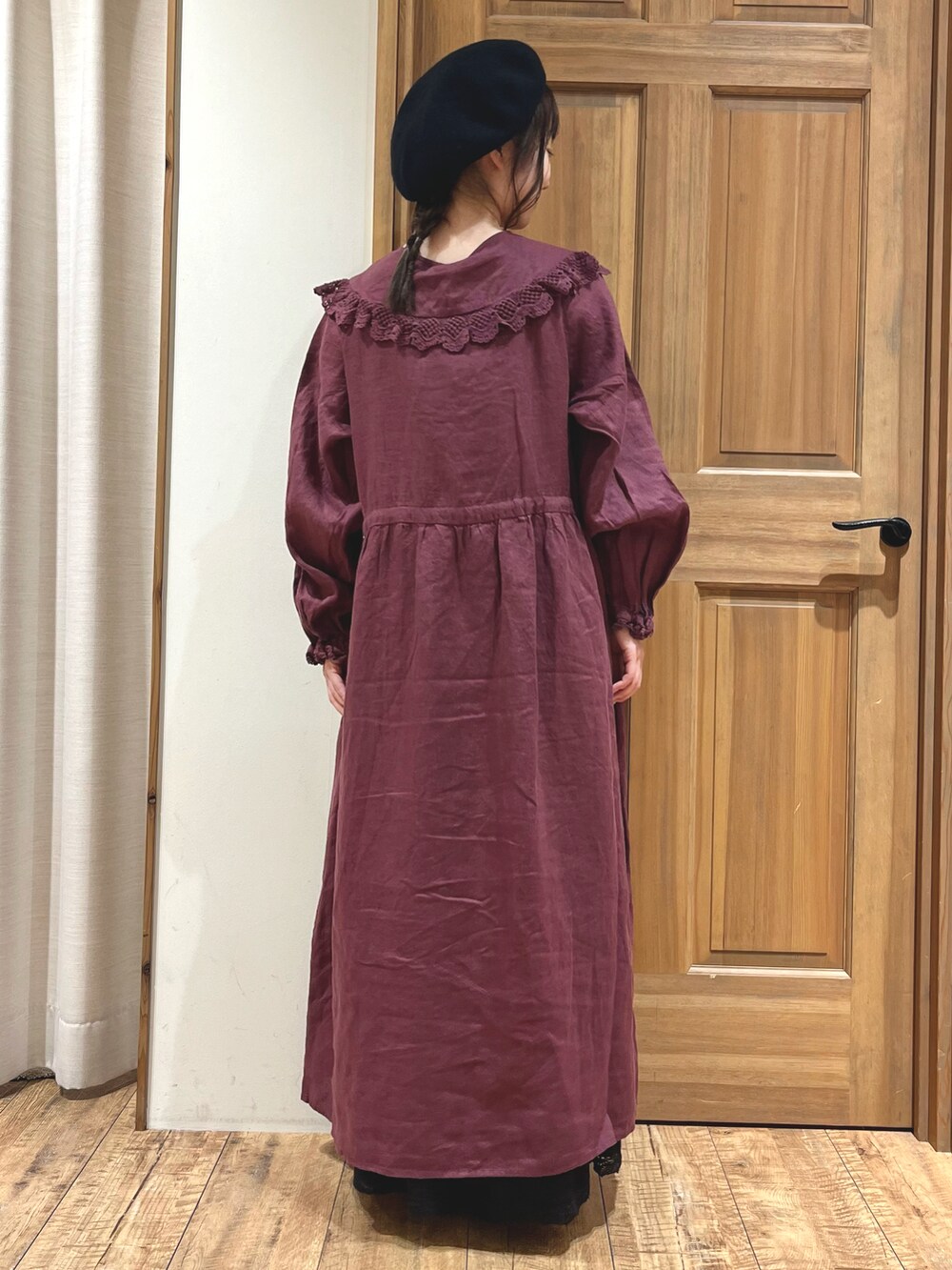 レッド系のワンピース、ブラック系のスカート、ブラック系のブーツを着用したレディースの秋コーディネートの4枚目の写真