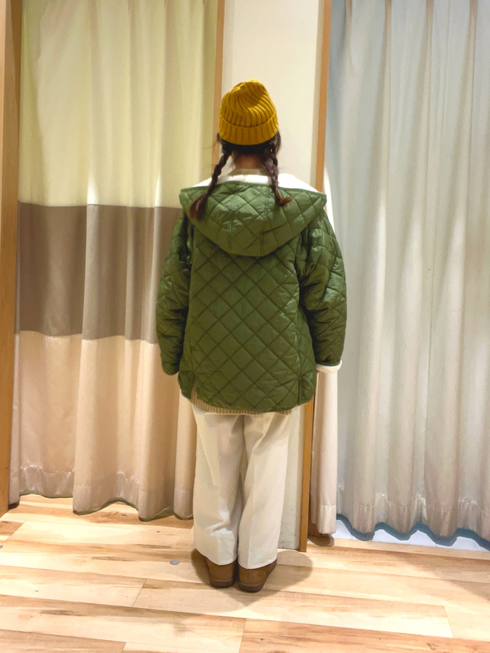 グリーン系のブルゾン、ベージュ系のニット/セーター、ホワイト系のその他パンツを着用したレディースの冬コーディネートの3枚目の写真