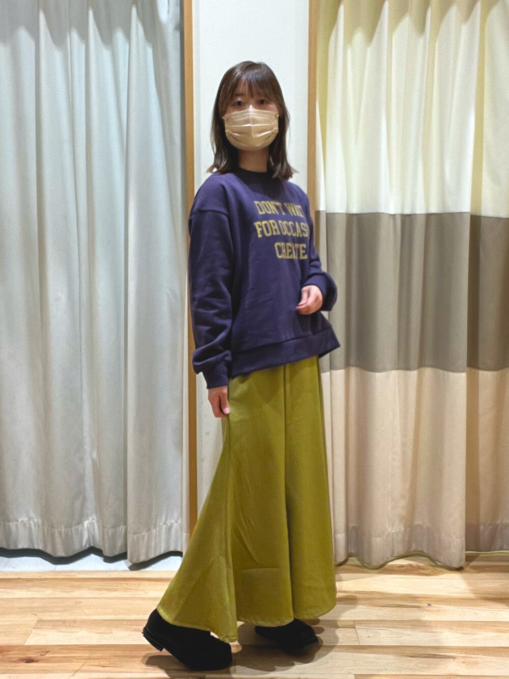 パープル系のTシャツ/カットソー、ホワイト系のマウンテンパーカー、イエロー系のスカートを着用したレディースの冬コーディネートの4枚目の写真